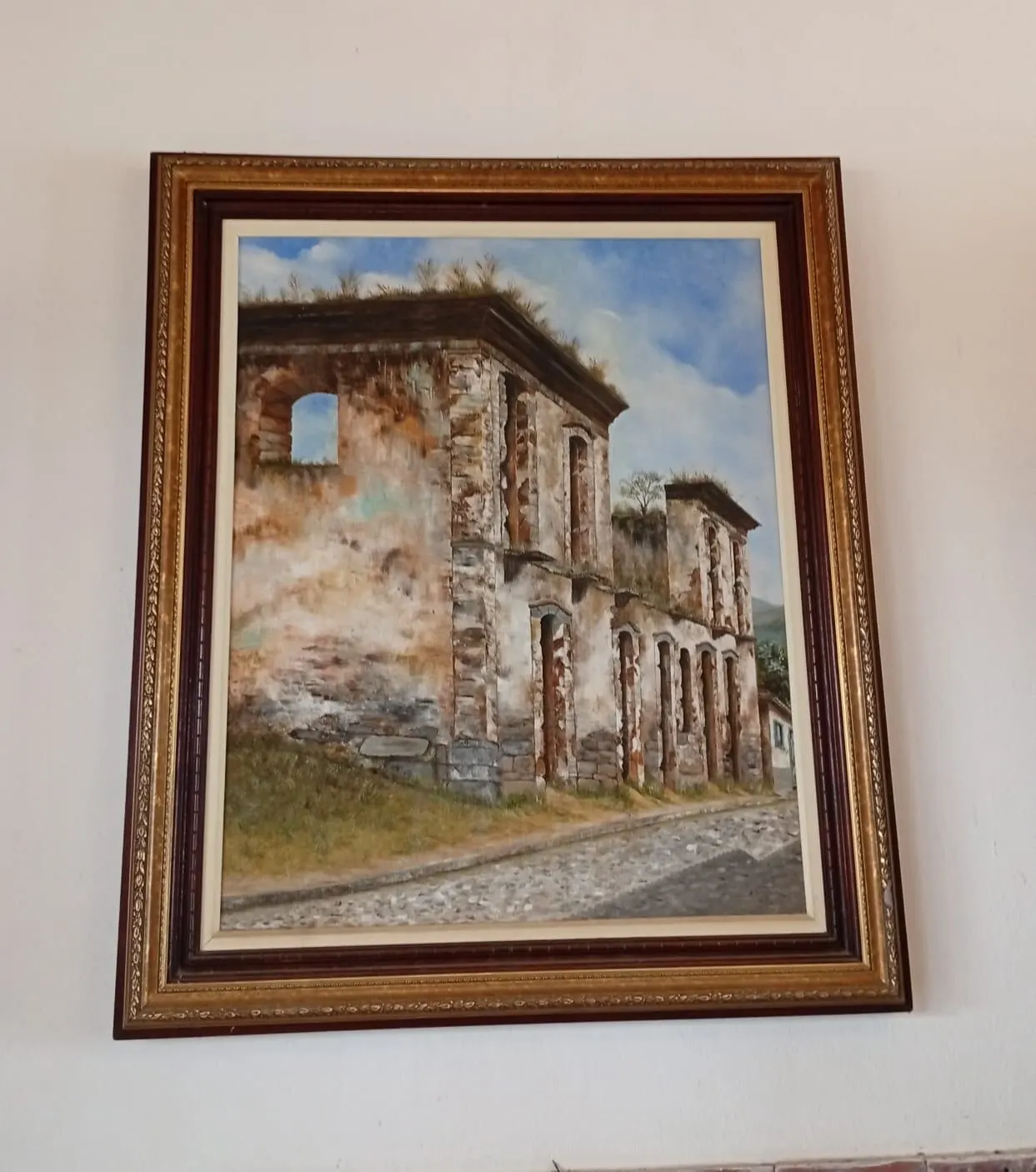 Pintura de ruínas históricas em moldura dourada