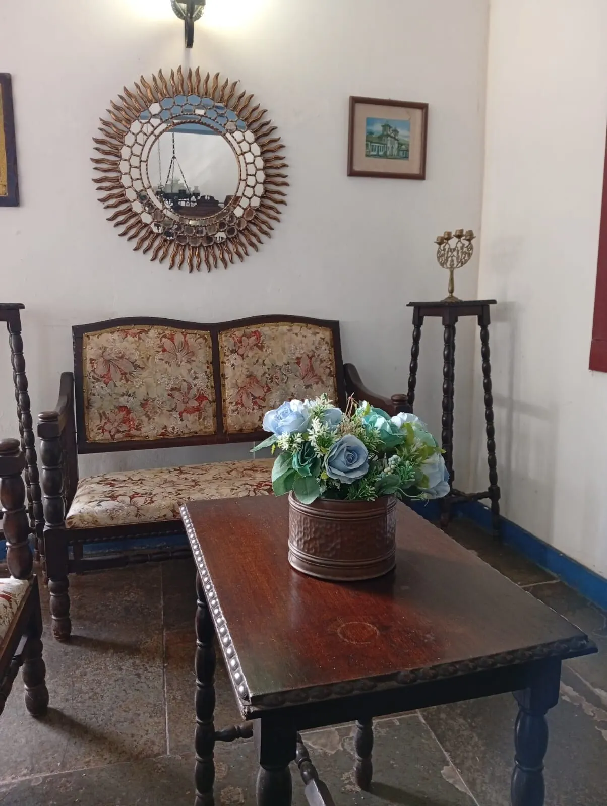 Sala de estar com sofá floral e espelho dourado
