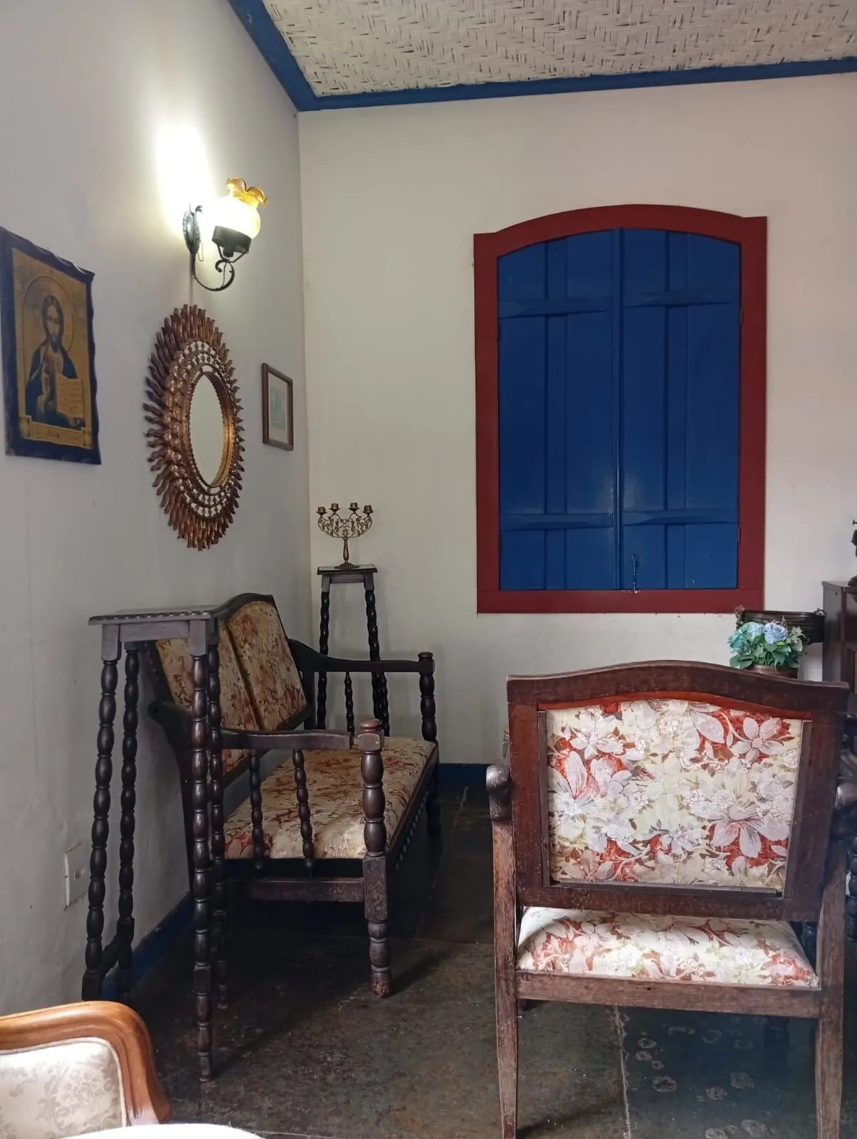 Sala íntima com janela azul e iconografia sacra