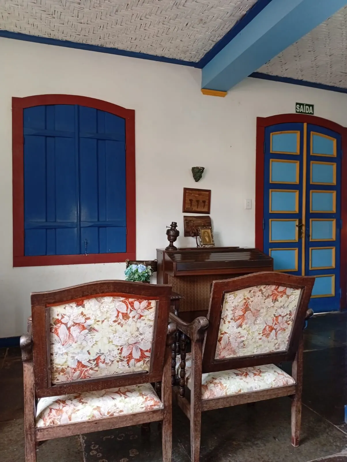 Sala com janelas azuis e poltronas florais